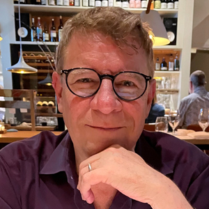 A person poses for a headshot while seated indoors.
