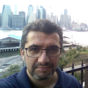 A person poses for a headshot in front of the New York City skyline.