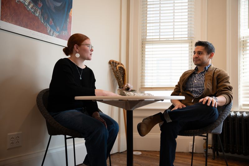 Two people sit at a small table, engaged in conversation.
