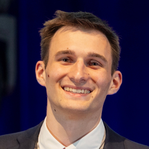 A student smiles in front of a dark backdrop.