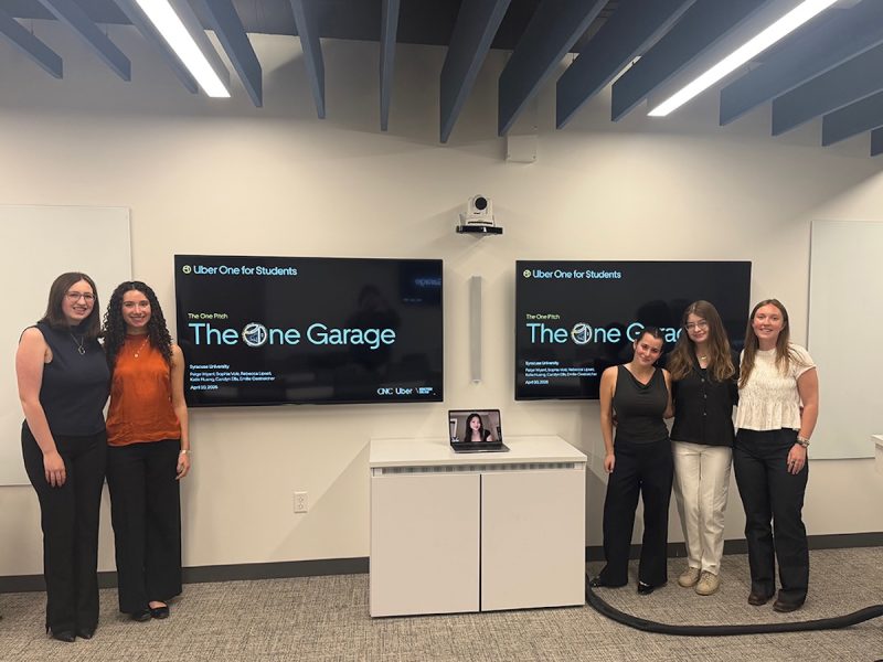 Students present The One Garage pitch during a classroom session, with presentation screens displayed behind them.