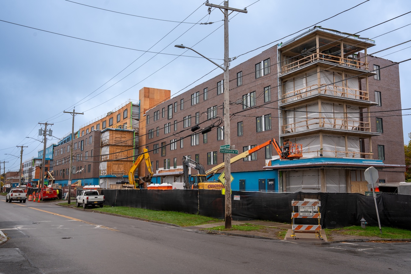 Residence hall under construction along a city street with construction equipment and scaffolding.