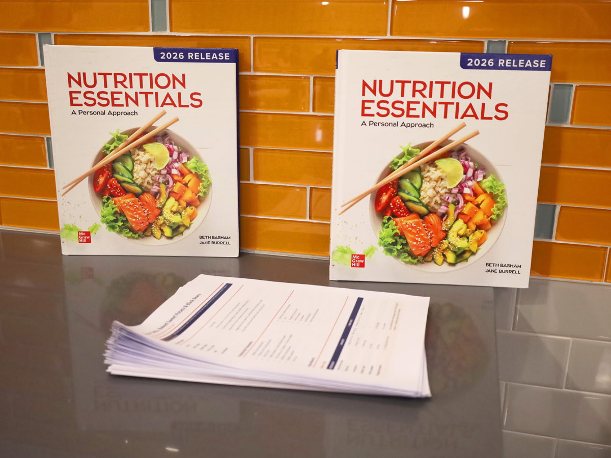 Two copies of the textbook "Nutrition Essentials: A Personal Approach" beside a stack of recipe handouts.