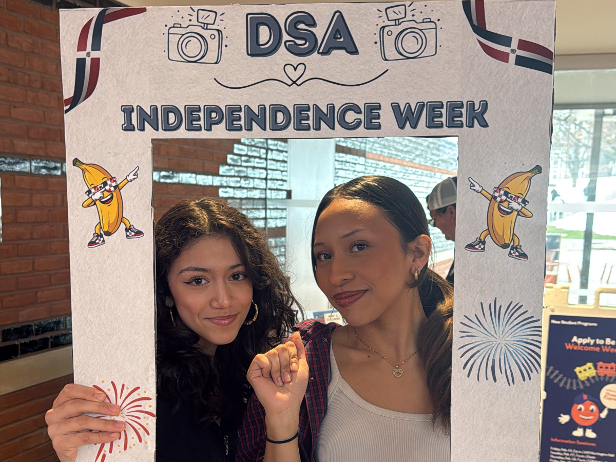 Two students smile through a cardboard photo frame reading "DSA Independence Week.
