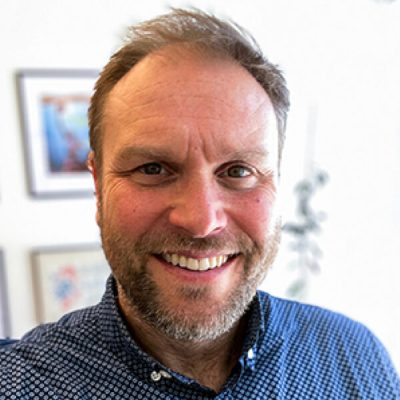 A person smiles while posing for a headshot.