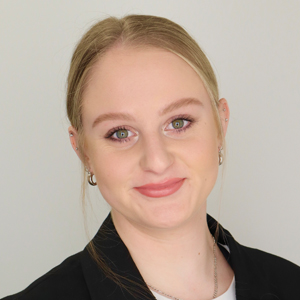 A person smiles while posing for a headshot indoors.
