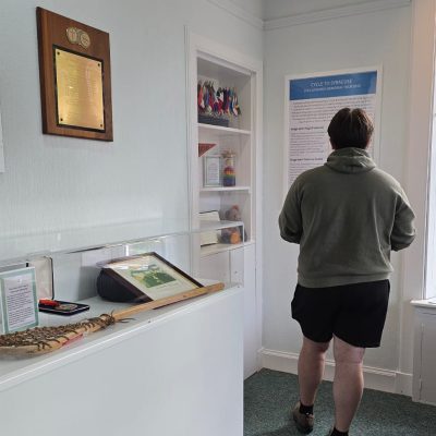 Visitor reads an exhibit panel on the Lockerbie Memorial Tour beside a display case