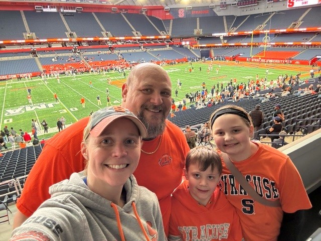 Matt Tarullo takes a selfie with his family while they each wear Syracuse orange gear in a the Dome.