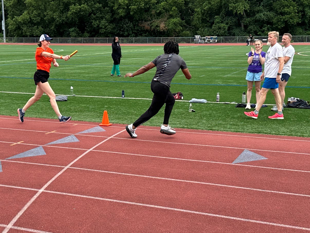 A runner tries to catch up to a teammate and hand off the baton during a relay race.