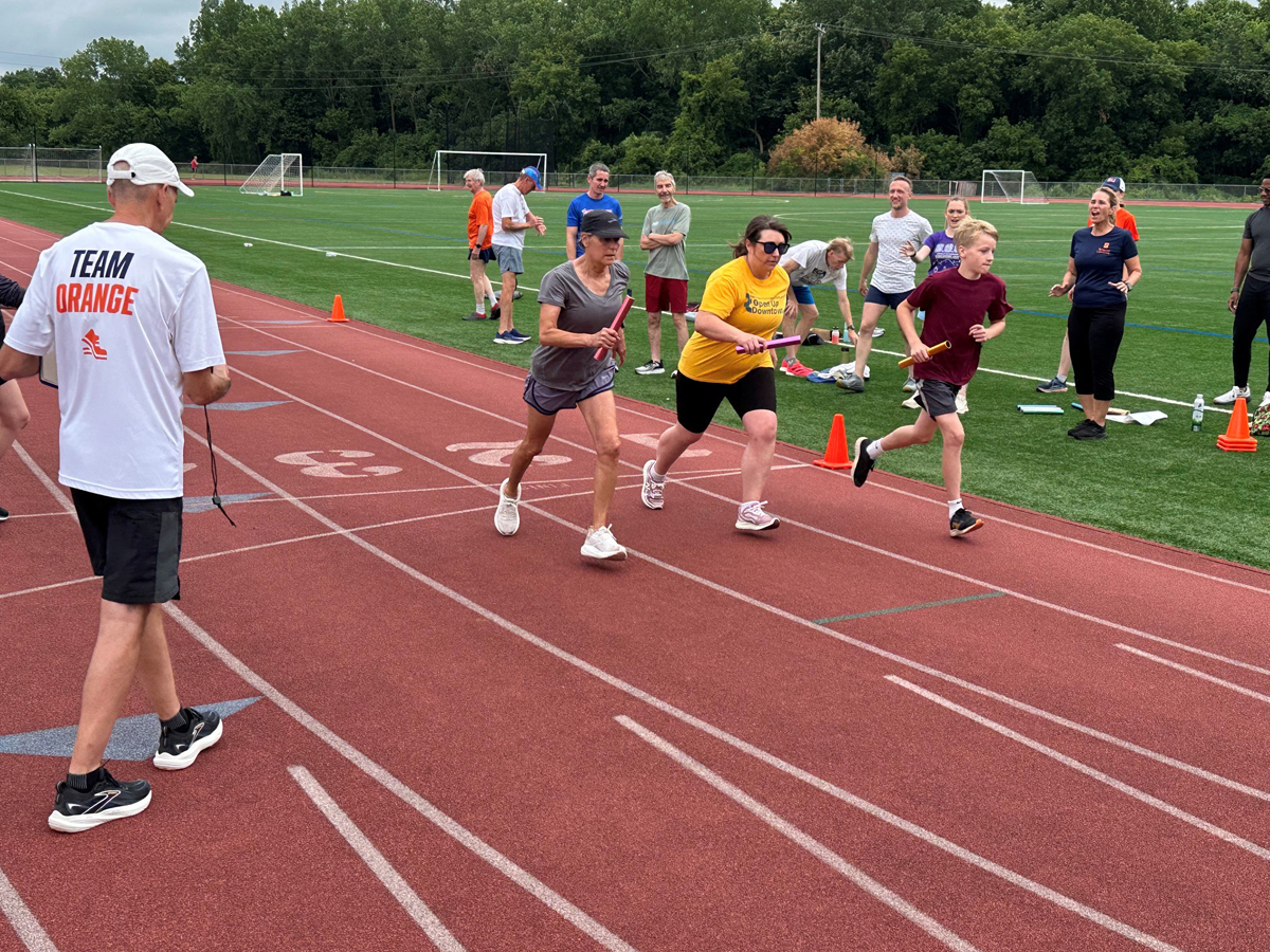 Three runners take off from the starting line during a relay race.
