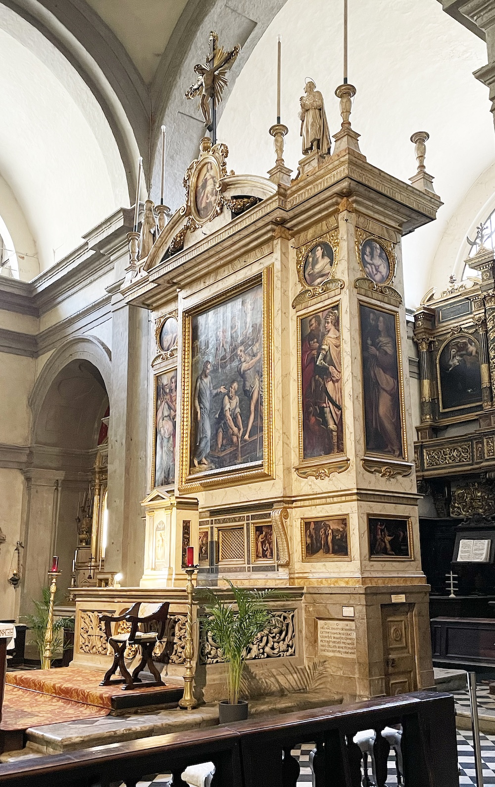 Ornate marble high altar inside a church, decorated with religious paintings, statues, and gilded architectural details.