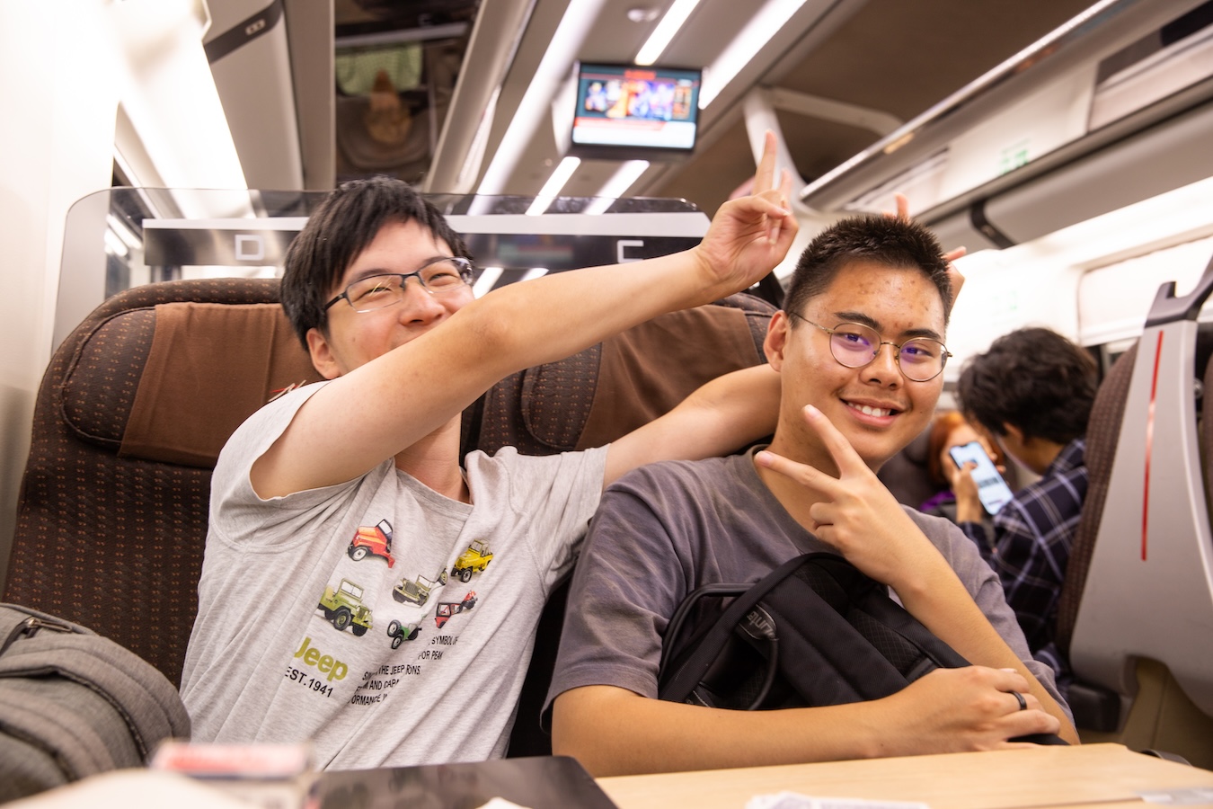 Students seated on a train pose for a photo during a group trip.