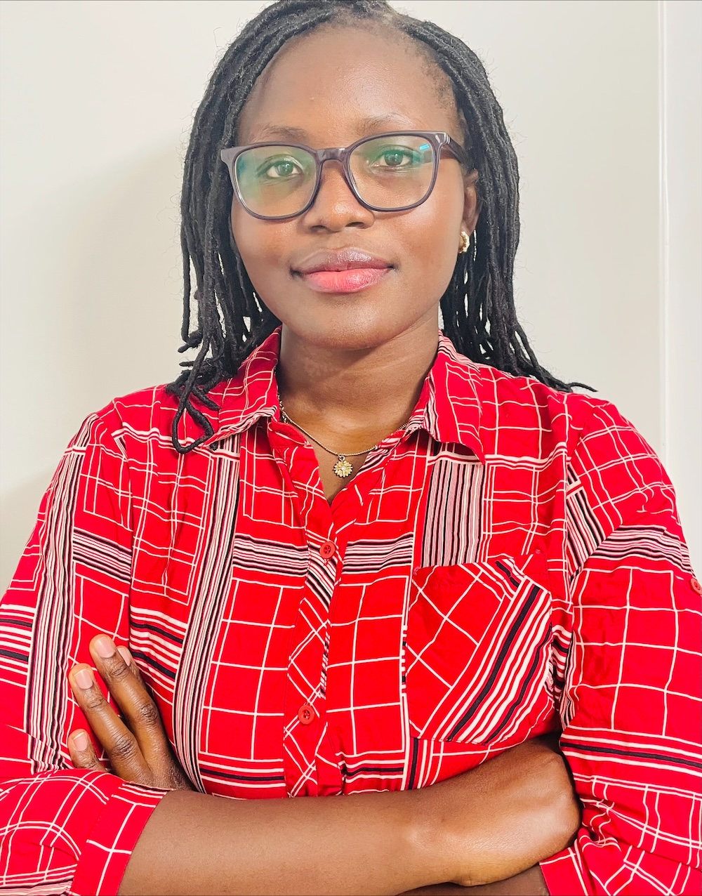 Professional portrait of a person wearing glasses and a red patterned shirt with arms crossed against a neutral background.