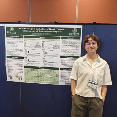 Researcher stands beside a scientific poster presentation at Upstate Medical University.
