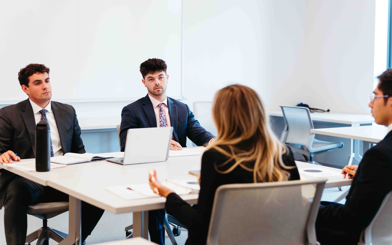 Participants in business attire seated around a conference table during a discussion.